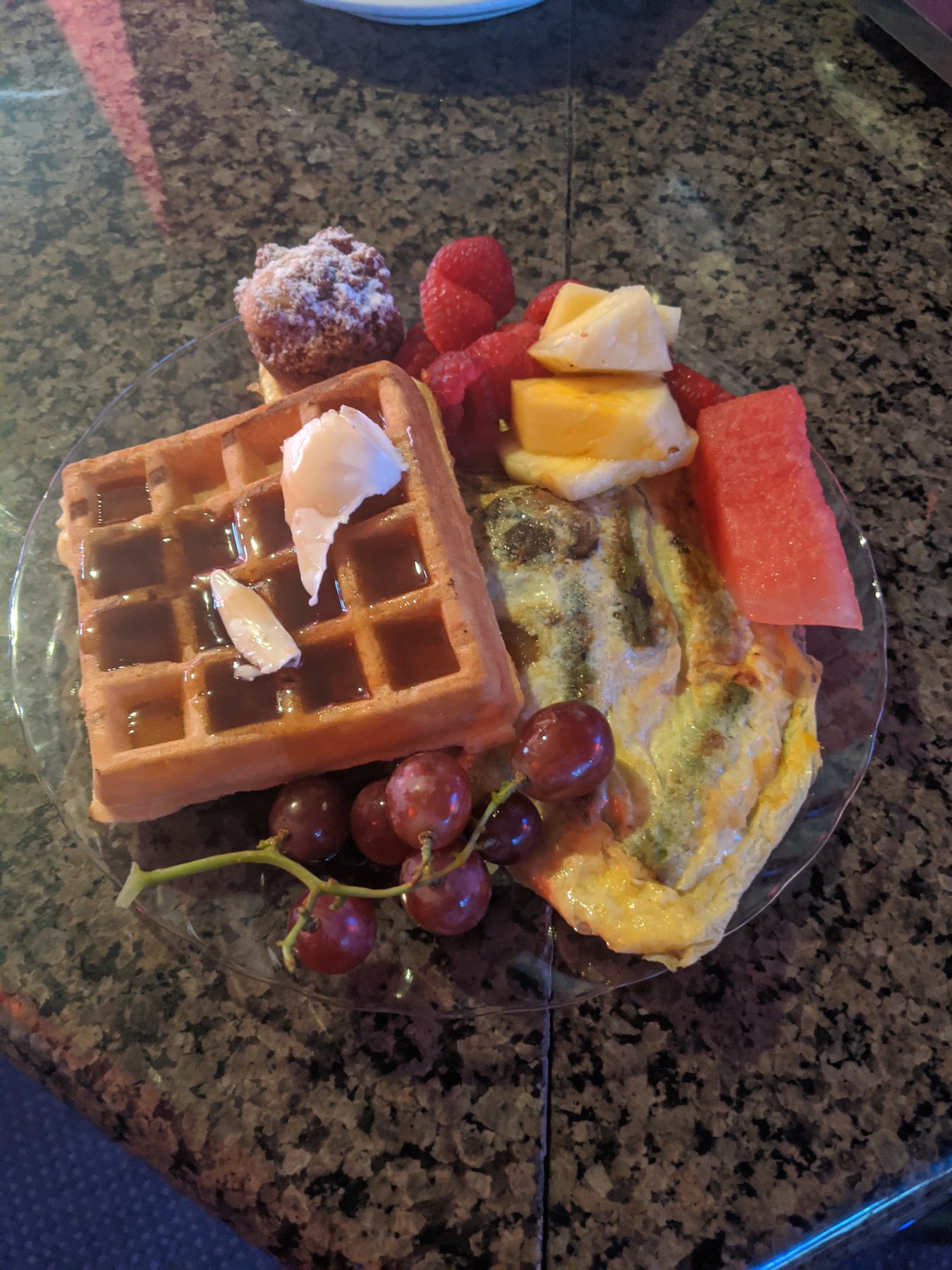 A brunch plate with a waffle, omelet, fresh fruit and a pastry