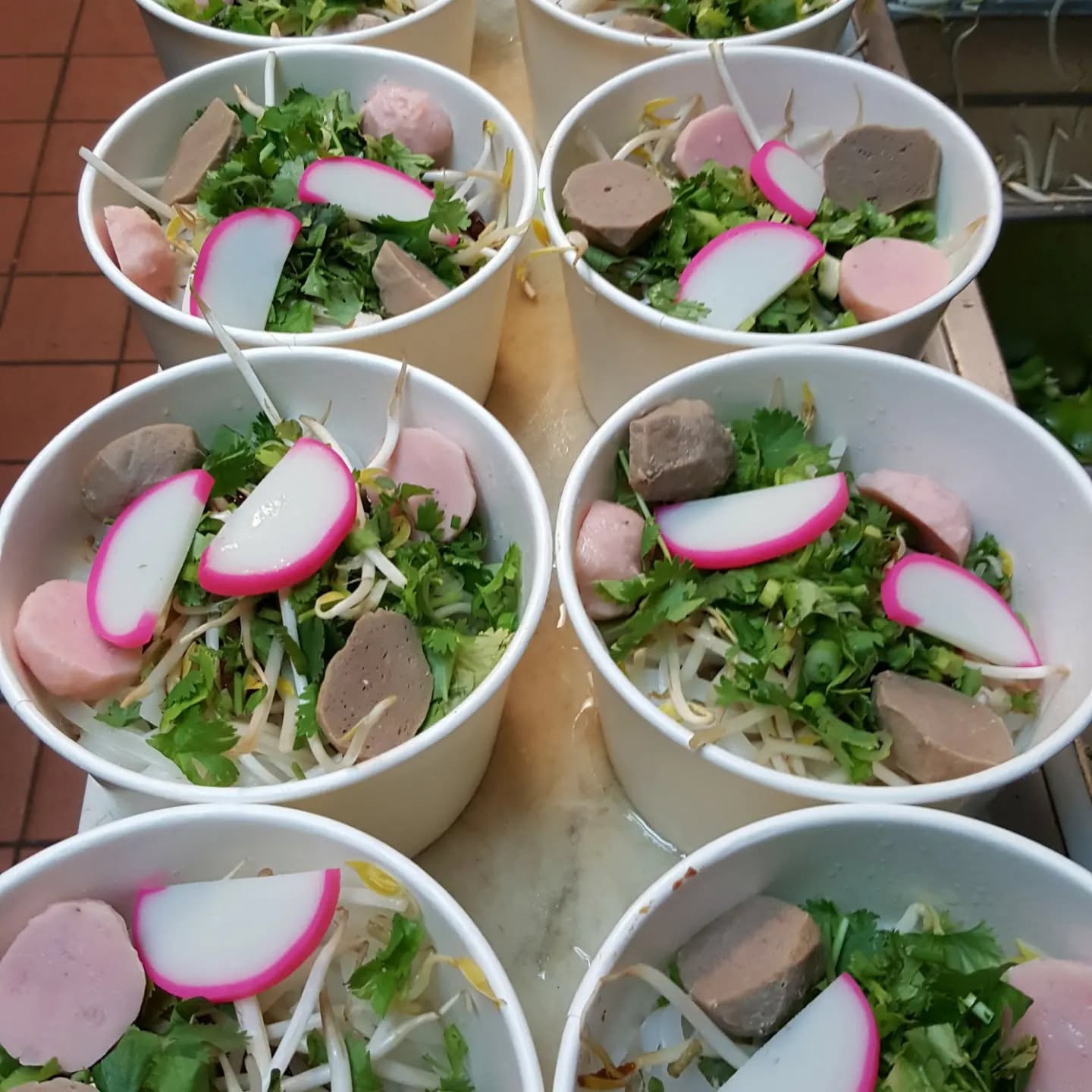Cups of fresh food topped with herbs and radish, ready to serve
