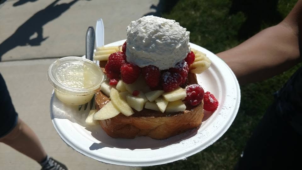 A plate of French toast topped with whipped cream and fresh berries