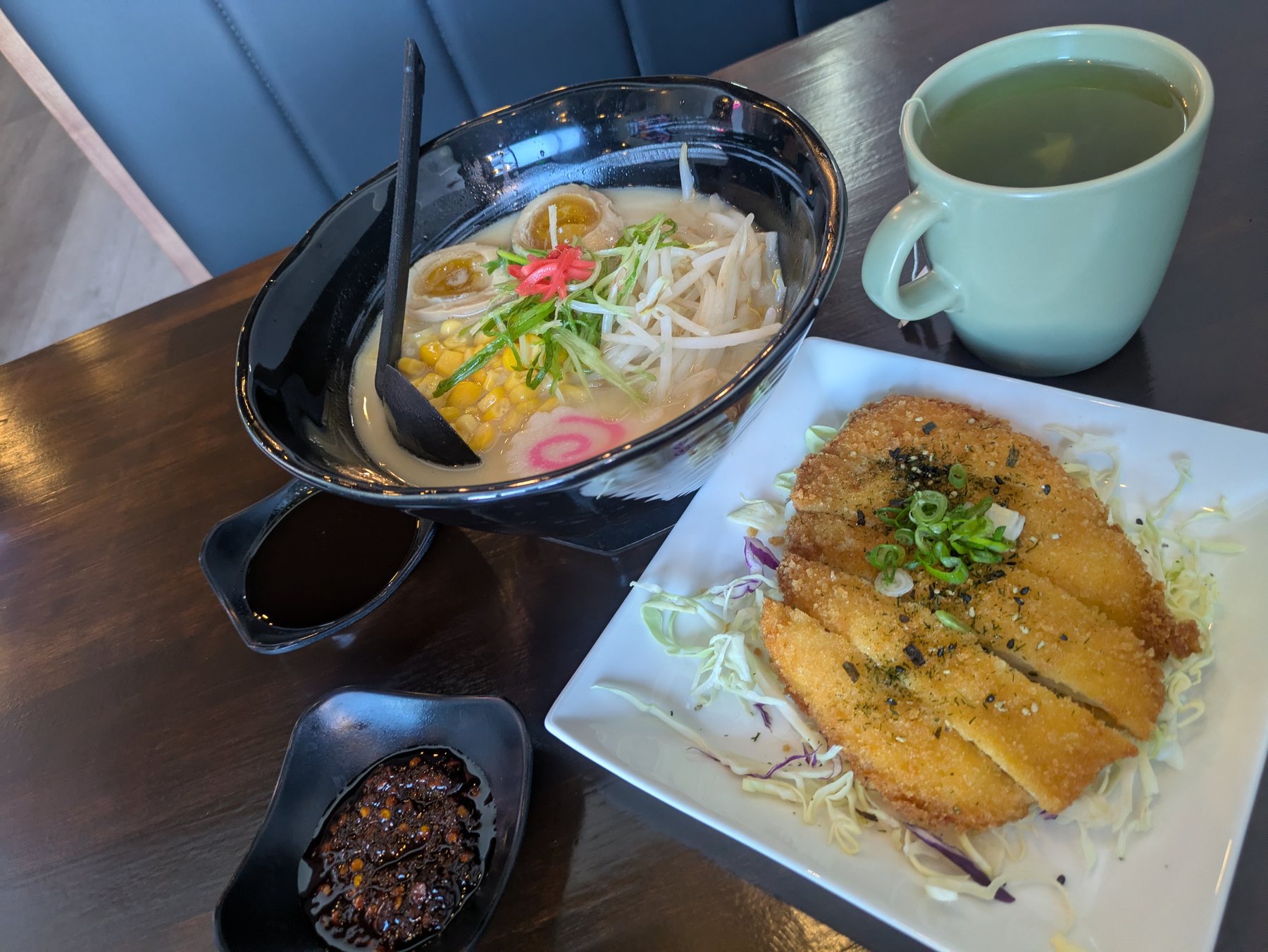 A bowl of ramen with chicken, served with a side dish