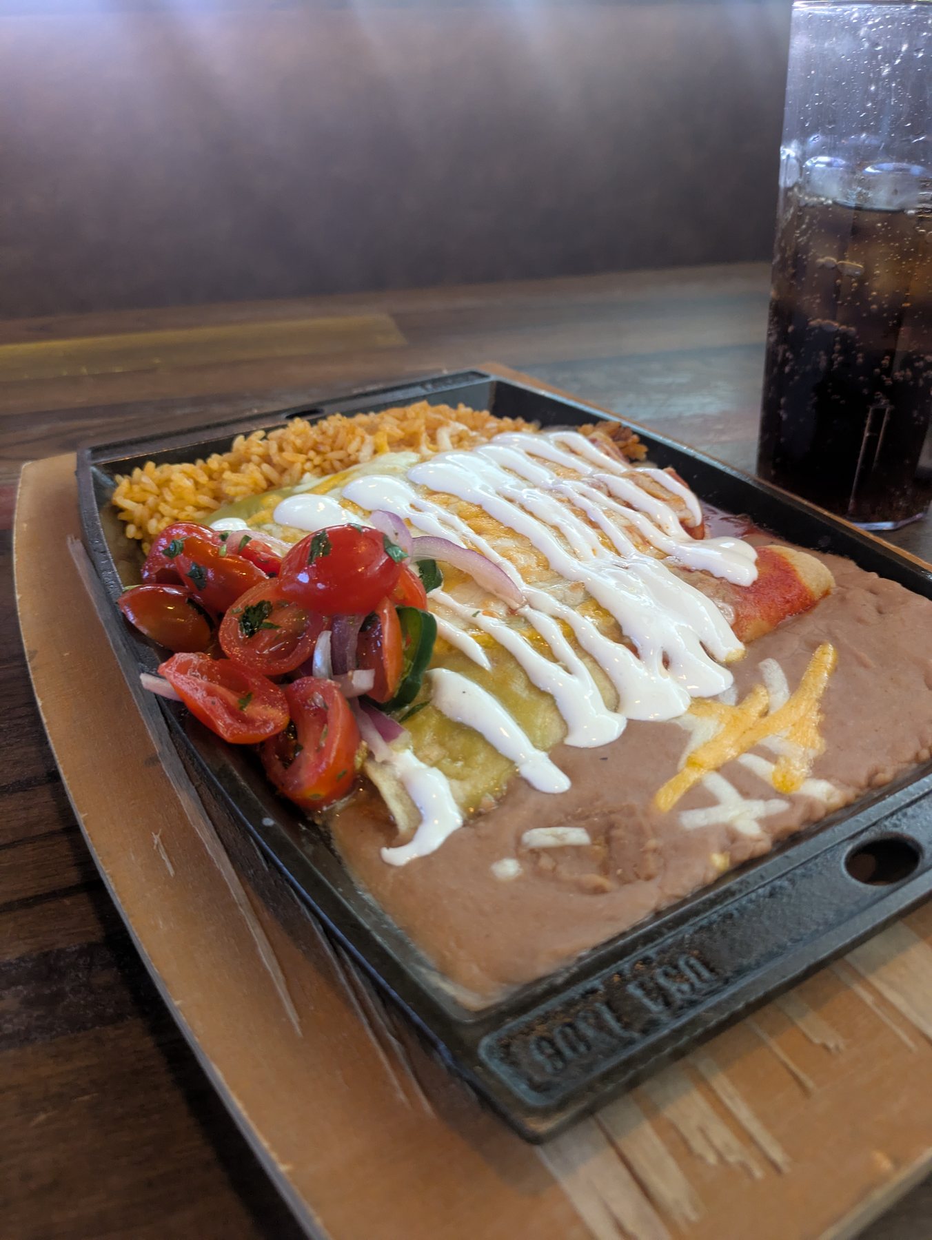 A sizzling plate of enchiladas with rice, beans and fresh tomato salsa